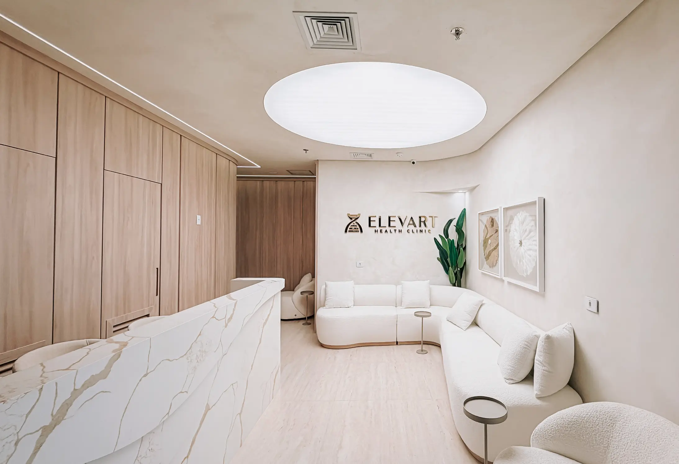 Recepção moderna da clínica Elevart com sofá branco em L, balcão de mármore e decoração minimalista.